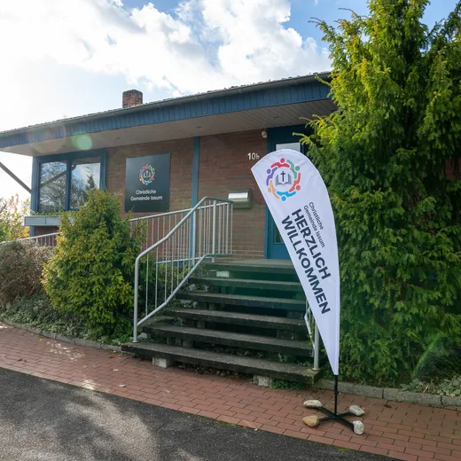 Das Gemeindehaus mit einer Fahne „Herzlich willkommen“ am Eingang